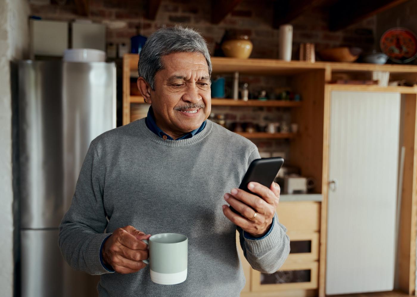 Señor sonriendo mientras confirma su operación en el celular